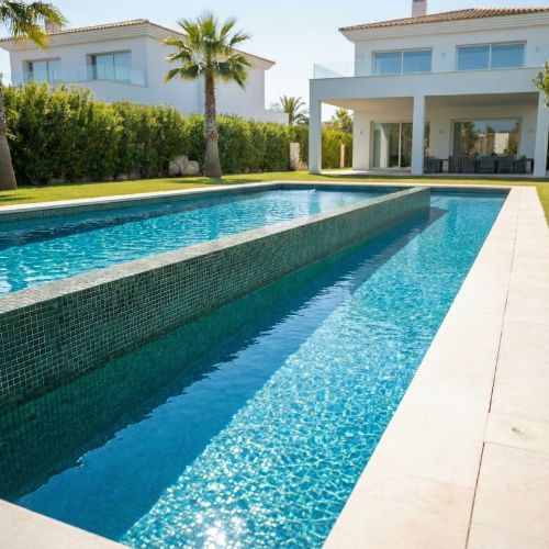 Resultado final de una rehabilitación de piscina de lujo con agua cristalina y diseño moderno, servicio integral de RepararPiscina.com.