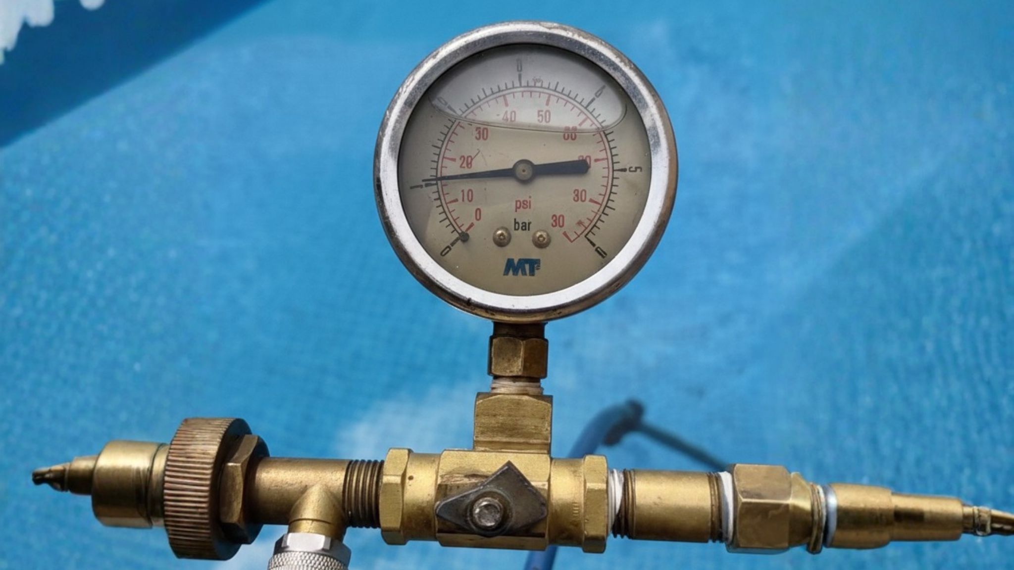 Manómetro industrial de alta precisión realizando una prueba de estanqueidad en el circuito hidráulico de una piscina con agua cristalina de fondo